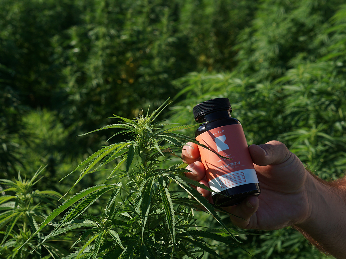 Hand Holding CBD Bottle In Forest 